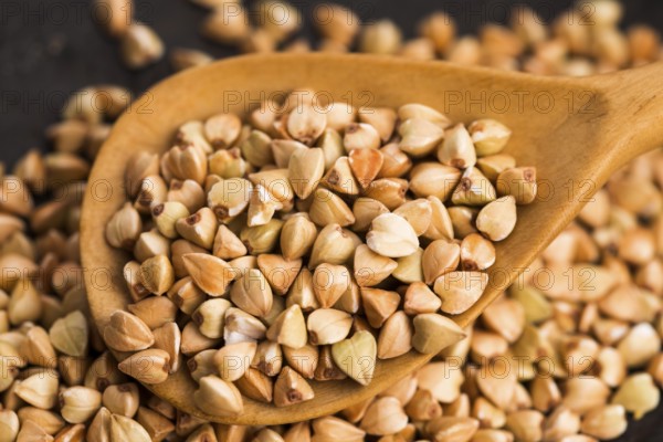 Buckwheat with a spoon on a wooden boards background