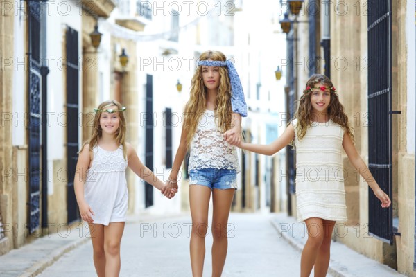 Kid girls walking hand in hand at white Mediterranean village of Spain
