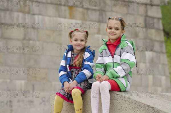 Two girls of four and six years of walking on the embankment of the river