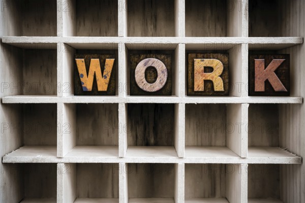 The word WORK written in vintage ink stained wooden letterpress type in a partitioned printer's drawer