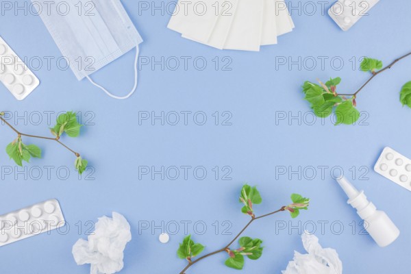 Creative flat lay concept of seasonal spring pollen allergy with napkins, pills, face mask, drops in a bottle and fresh green sprouts with buds. copy space background minimal style, template for text