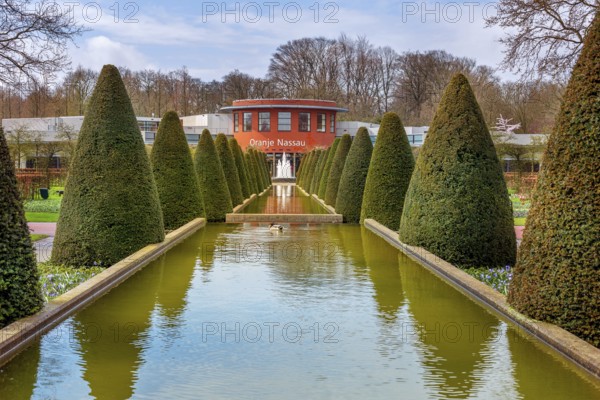 Lisse, Netherlands, April 4, 2016: Spring landscape, touristic park with water fountain and Oranje Nassau pavilion in Keukenhof