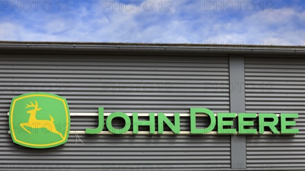 John Deere logo outside on building exterior with blue sky and clouds. Salo, Finland. June 25, 2023