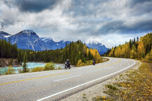 Motorcyclists driving on the road. The concept of active tourism. The astonishing nature of the Rockies of Canada. The road 93 Icefields Parkway passes among the snow-capped mountains