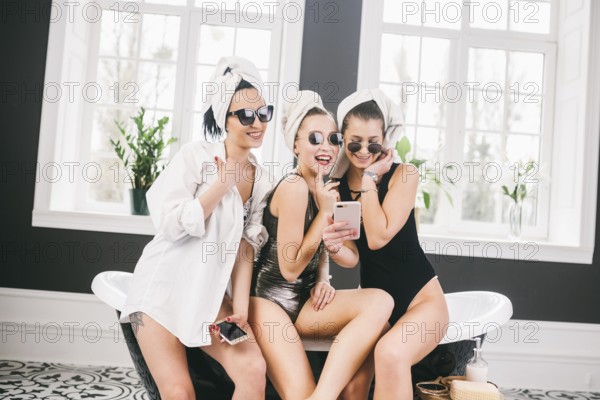 Picture showing group of happy friends in spa. girls with towels on heads having fun and taking selfie at home. Friendship, cosmetic, slumber party concept. Hen party with a bride in hotel