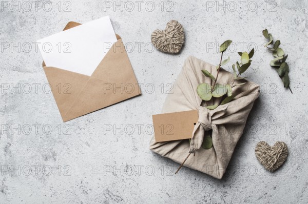 Zero waste Valentine's Day concept and mock up. Eco-friendly gift cloth wrapping in Furoshiki style, craft paper envelope, empty gift or greetings card. Top down view or flat lay. Copy space for design