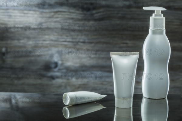Tubes and sprayer skincare items on dark background