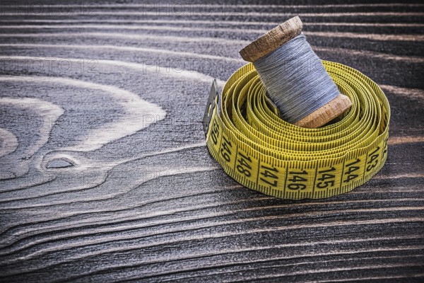 Vintage spool of thread tape measure on wooden board handicraft concept