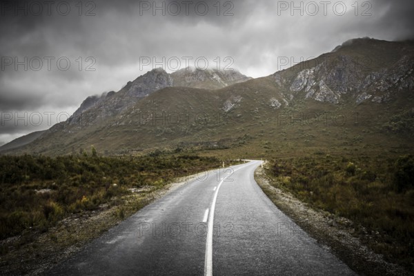 The picturesque Gordon River Rd at the Sentinel range of mountains near Bitumen Bones Sculpture on a cool wet summer's morning in Southwest National Park, Tasmania, Australia, Oceania