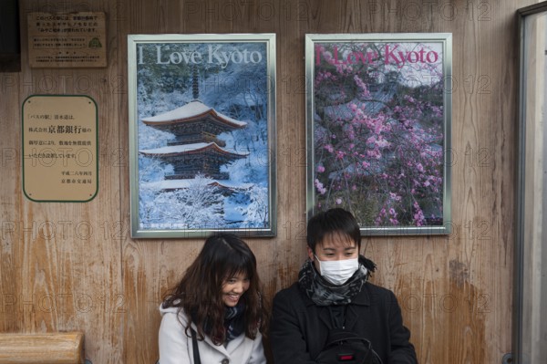 24.12.2017, Kyoto, Japan, Asia, A young couple sits at a bus stop in front of two posters advertising the city with the slogan I Love Kyoto, Asia