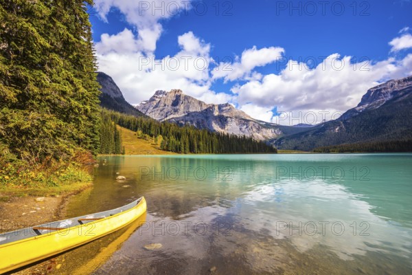 Sunny day in autumn Yoho National Park. In shallow water, the boat is moored. The concept of eco-tourism and active tourism. The mountain Emerald lake