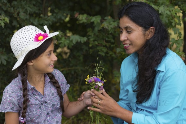Girl gives mum a bouquet of flowers she picked herself