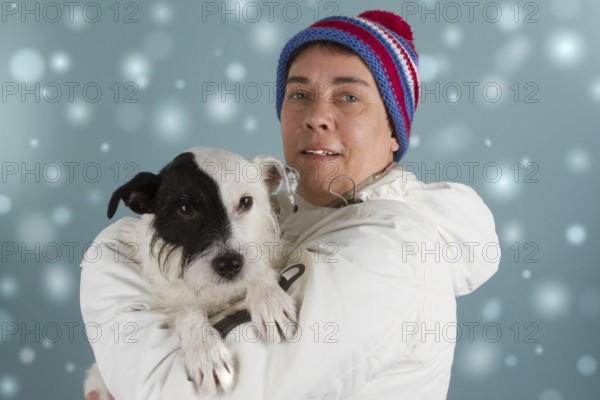 Woman with small dog in winter clothes in the snow