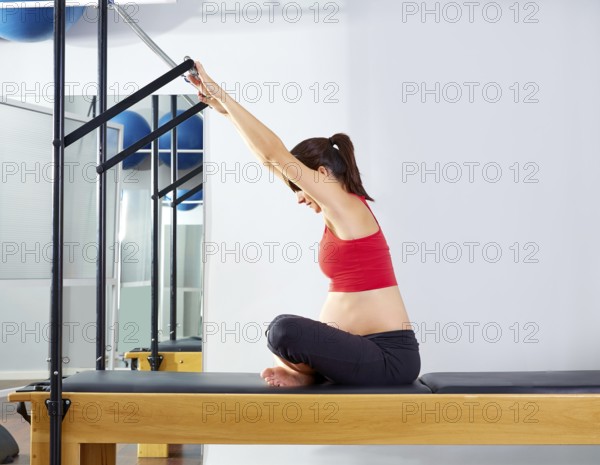 Pregnant woman pilates reformer forward push through exercise workout at gym