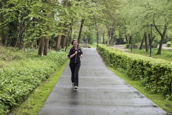 Jette, Brussels Capital Region Belgium, 04 24 2020 Attractive thirty year old woman jogging through the park
