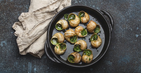 Escargots de Bourgogne Cooked Snails with Garlic Butter and Parsley in black cast iron pan on rustic stone background top view, traditional French Delicacy, food photography, food photography