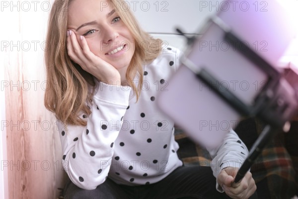 Blogging. Blonde girl blogger Technology internet and happiness concept. Young woman funny girl taking self picture selfie with smartphone camera on stick at home. Storytelling
