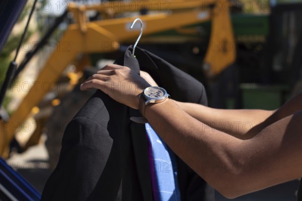 Closeup of an unrecognizable latino man putting an american jacket on a hanger outside