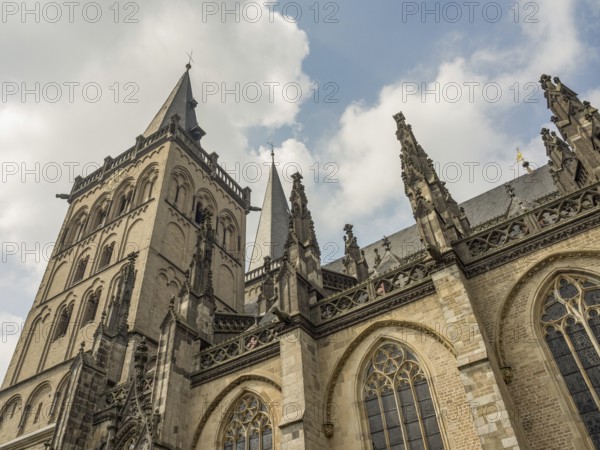 Impressive Gothic building with high towers and detailed decorations under a slightly cloudy sky, xanten, lower rhine, germany