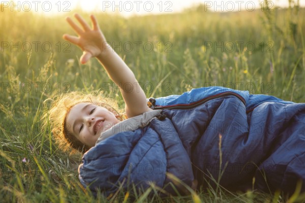 A child sleeps in a sleeping bag on the grass in a camping trip, eco-friendly outdoor recreation, healthy lifestyle, summer time. Sweet and peaceful sleep. Mosquito bites, repellent