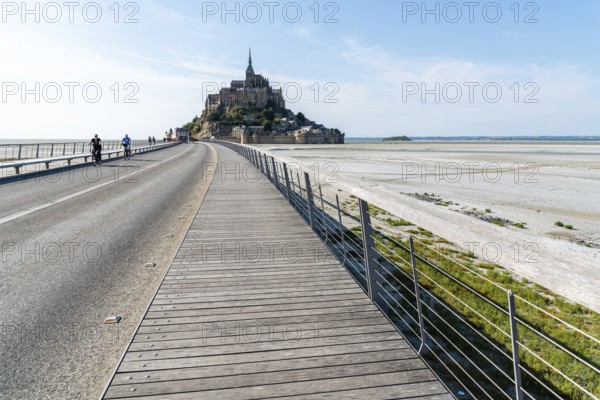 Mont Saint Michel, France, July 25, 2018: View of Mont Saint-Michel against sky. Cyclists on the boardwalk, Europe