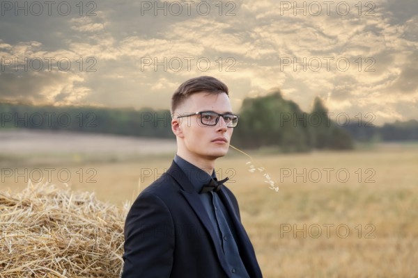 Young man with glasses thinking and standing on the field, vintage instagram toning