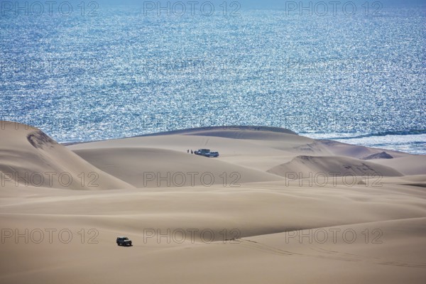Gorgeous and dangerous jeep - safari through the huge sand dunes on the ocean shore. Atlantic coast of Namibia, south of Africa. The concept of exotic and extreme tours