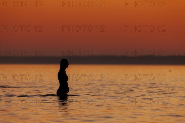 A woman cools down in a fresh water lake at the end of hot summers day