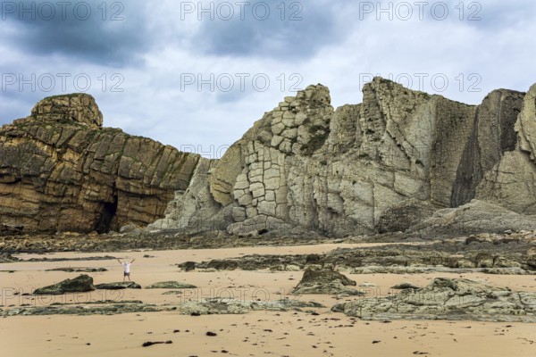 Noon on the beach of Playa di Arnia, Spain. Man admiring the magnificent scenery. Cantabria. Windy stormy day on the Atlantic coast