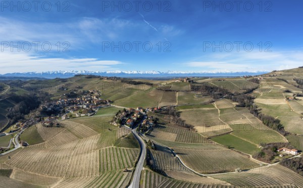 The hilly countryside in the Italian Piedmont with the village of Barolo and snow-covered mountains behind