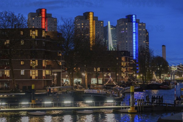 Urban scene with illuminated skyscrapers and bridge lights reflected in the water, Rotterdam, Netherlands