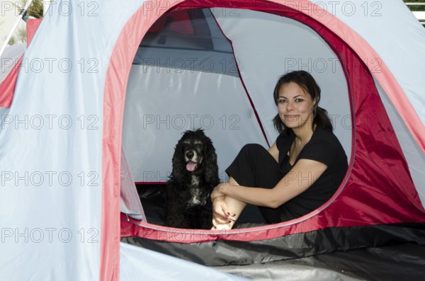 Woman Sitting Inside a Camping Tent with Her Cocker Spaniel Dog in a Sunny Summer Day in Switzerland
