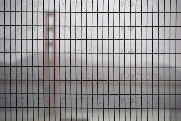 The Golden Gate Bridge blurred behind a fence in hazy rainy weather