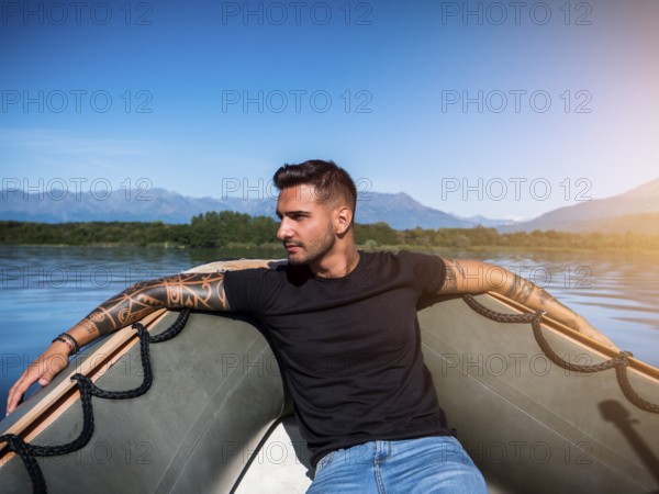 Portrait of young bearded handsome man with tattooed body looking sexually at camera sailing in boat