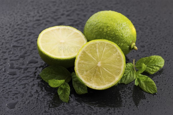 Green limes with mint and water drops on black background