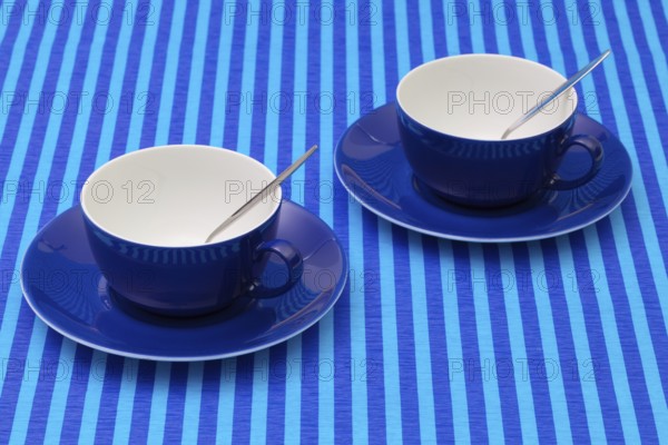 Symmetry arrangement empty cups of tea on blue striped tablecloth. Blue concept