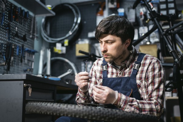 Bicycle mechanic fixing cycle wheel in repair shop. Velocipede service. Repairer male bike shop engineer fix bicycle wheel in workshop. Technician fixes bike parts. Handyman at work in the workplace