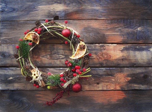 Christmas decoration on wooden background. Wreath with spice and red berries