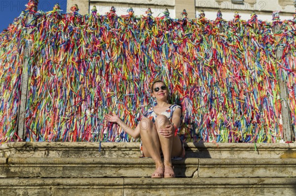 Young Woman in front of the grid with colored ribbons of Bonfim church in Salvador Bahia Brazil