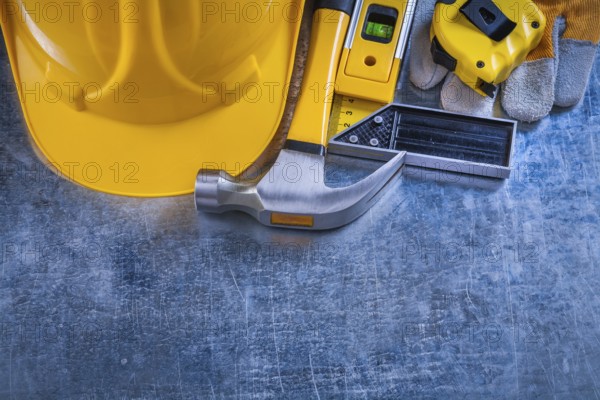 Safety gloves try square construction level tape-line hard hat and claw hammer on metallic background maintenance concept