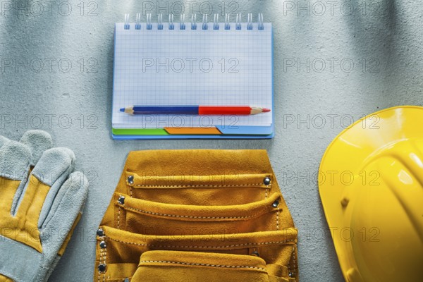 Protective gloves building helmet notebook pencil tool belt on concrete background