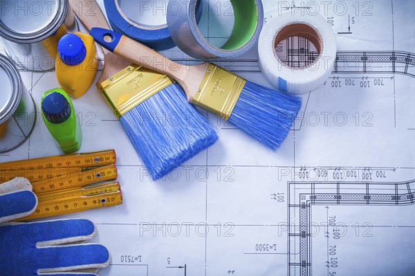 Wooden meter household tapes safety gloves and paint tools on blueprint maintenance concept