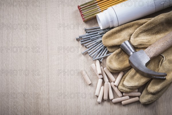Wooden meter dowels construction drawings claw hammer pair of safety gloves and nails on wood board maintenance concept