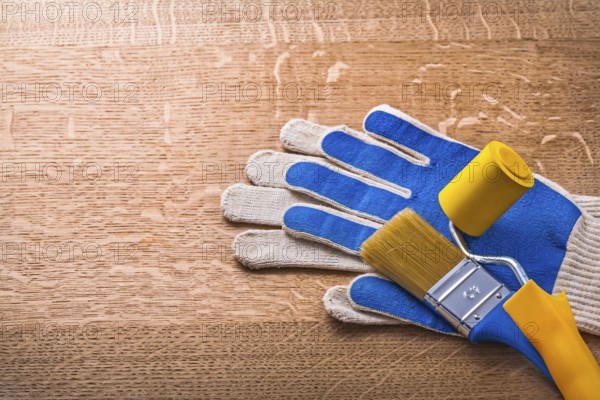 Protective gloves paint roller and brush on wooden board construction concept