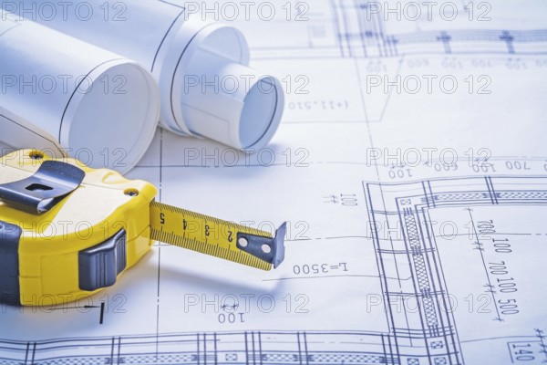 Close up view yello tapeline and rolls of blueprints horizontal version