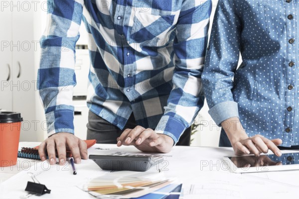Designers working with color swatches and tablet computer at desk. Interior design, architectural decoration and renovation. Brainstorm, teamwork and creativity. Decorator workplace in design agency