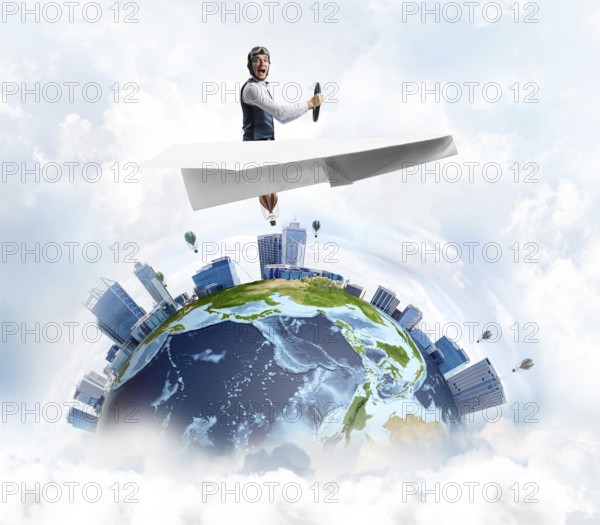 Pilot in leather helmet and goggles driving paper plane in cloudy blue sky. Funny man flying in small paper airplane over earth globe. Spherical view of modern city with high skyscrapers