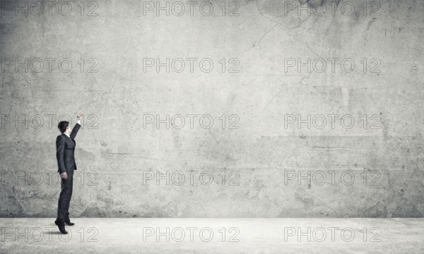 Businessman in empty concrete room drawing on wall