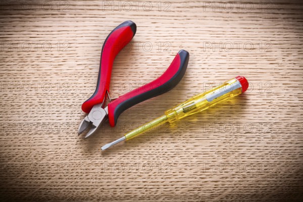 Electrical tester and pliers on wooden board
