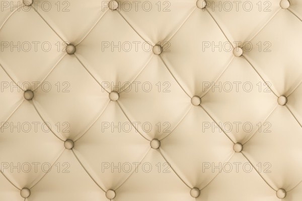 Beige soft tapestry pattern background with symmetrical buttons on the corners of diamonds. Soft and expensive furniture elements. Luxury background